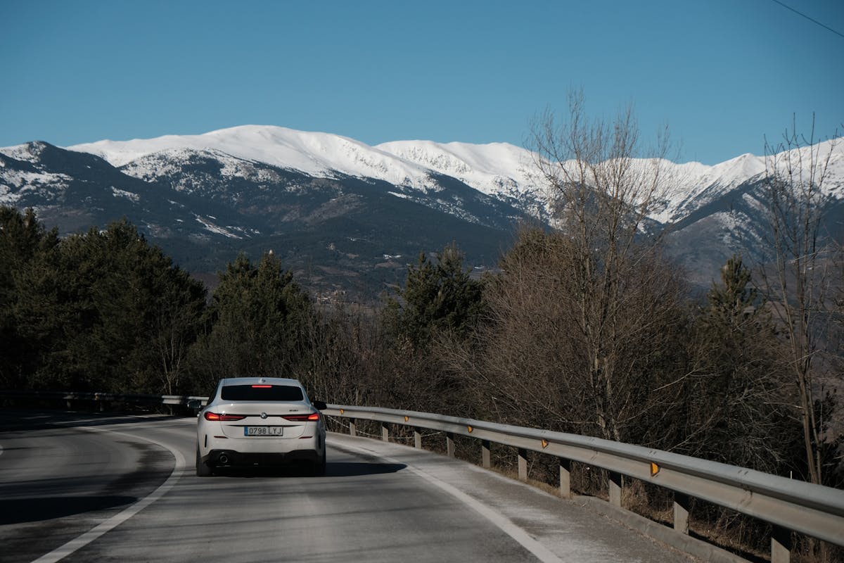 White sedan driving along a mountain road for an outstation trip